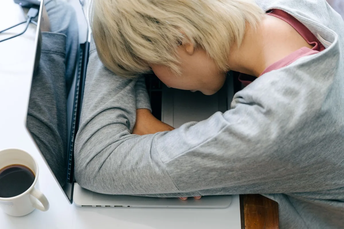 Personne fatiguée assise, main sur le front, exprimant l'épuisement