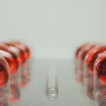 Gélule de vitamine B12 tenue en main avec tubes de test en arrière-plan flou