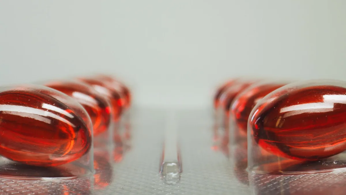 Gélule de vitamine B12 tenue en main avec tubes de test en arrière-plan flou