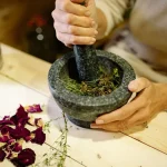 Mains tenant des feuilles de plantes fraîches et séchées avec des pots en verre, éclairage naturel doux