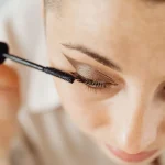 Application d'une base pour cils avec un pinceau de maquillage sur des cils bien séparés