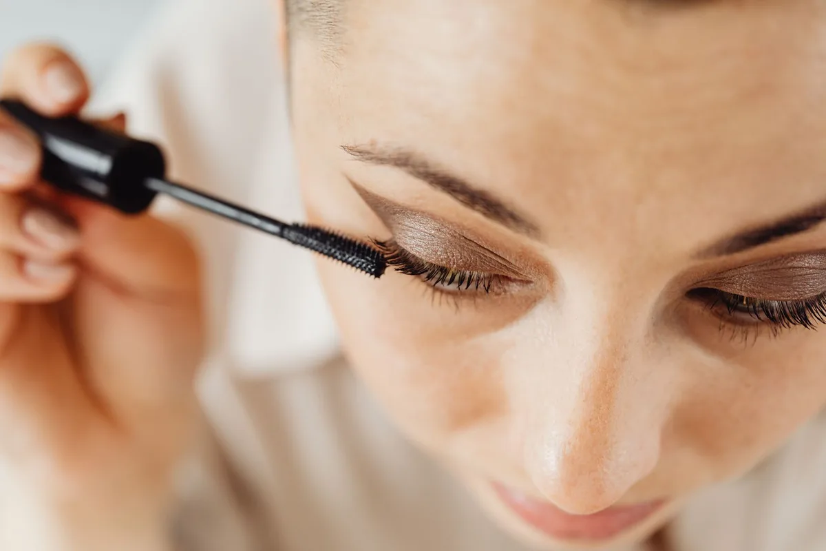 Application d'une base pour cils avec un pinceau de maquillage sur des cils bien séparés