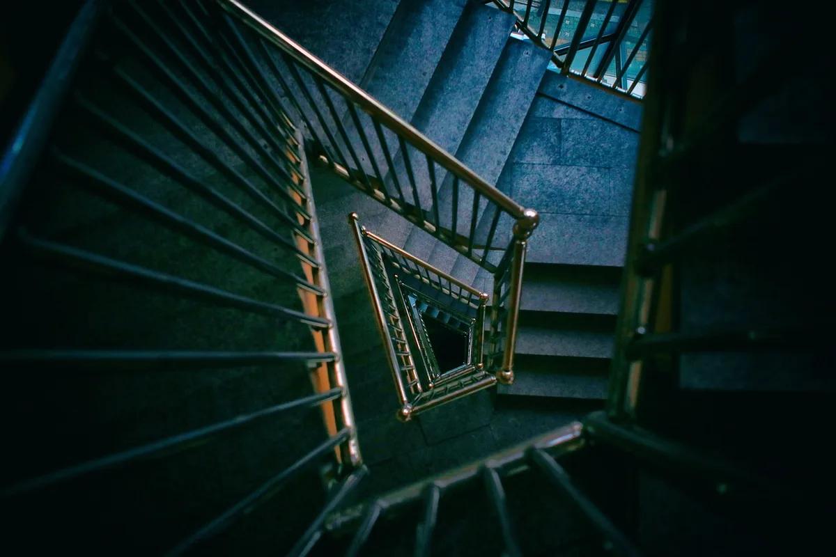 Personne essoufflée montant des escaliers, main sur la rambarde