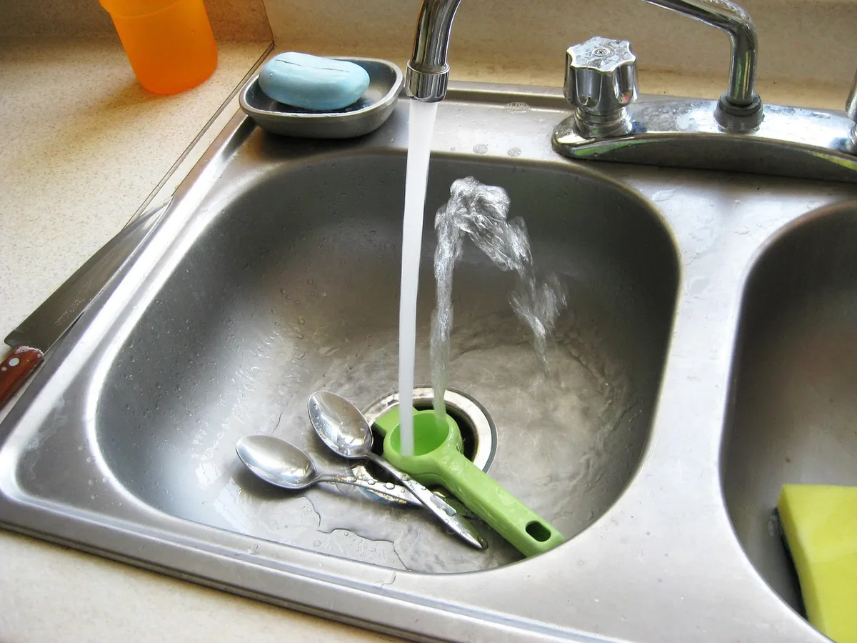 Mains lavant des feuilles de papaye au robinet
