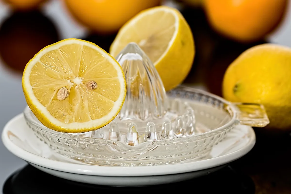 Carafe d'infusion et citron tranché sur une planche, lumière du jour