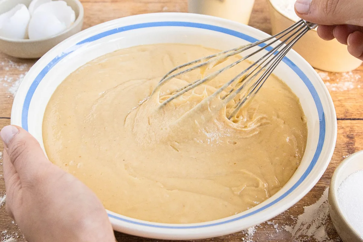 Mains mélangeant une pâte à pain sans gluten dans un saladier