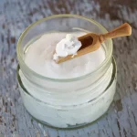 Application d'une petite quantité d'huile de coco sur les longueurs des cheveux près d'une fenêtre